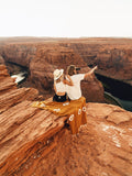 Two people enjoying nature wrapped in a Peace Blanket at a scenic canyon view, capturing a peaceful moment.