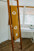 Cozy handwoven Peace Blanket from Trek Light on wooden ladder, made from recycled clothing materials.