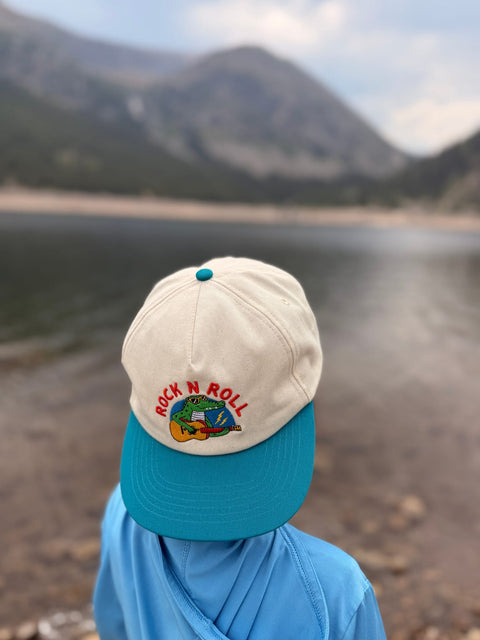 Child wearing a Rock N Roll Kids Hat while enjoying outdoor adventures near a lake.