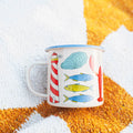 Salty Seas Enamel Mug 16oz with nautical design, featuring lighthouse, fish, and ocean motifs, perfect for cozy mornings and campfires.