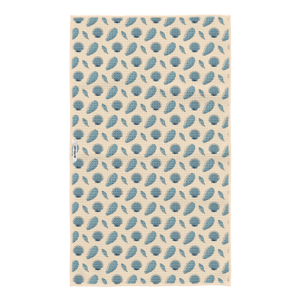 Reverse side of Salty Seas kitchen tea towel with blue scallop shell, oyster and clam pattern on cream, Trek Light logo tag