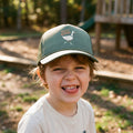 A child wearing a Silly Goose Kids Hat, smiling joyfully with a playful expression on a sunny day outdoors.