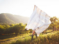 Person holding the Silverton Blanket with geometric stripes outdoors, highlighting its sustainable, handwoven design from recycled materials.