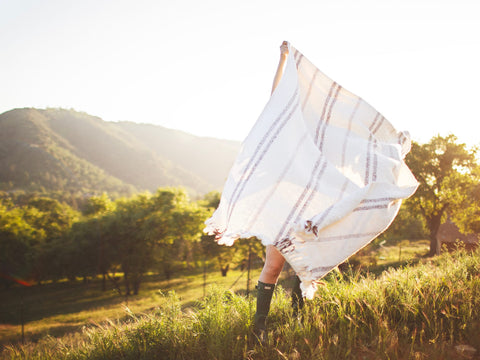 Person holding the Silverton Blanket with geometric stripes outdoors, highlighting its sustainable, handwoven design from recycled materials.