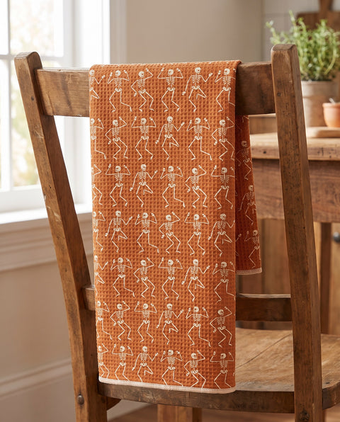Skeleton Party waffle kitchen tea towel draped over a wooden kitchen chair, front print facing out