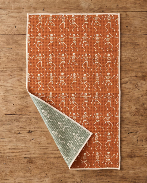 Skeleton Party waffle kitchen tea towel flat lay with a corner folded up to reveal the reverse print