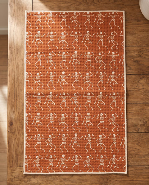 Skeleton Party waffle kitchen tea towel laid flat on a wood counter showing the full front print