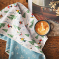 Snow Day Kitchen & Tea Towel with festive winter design, eco-friendly and super absorbent, next to a coffee cup.