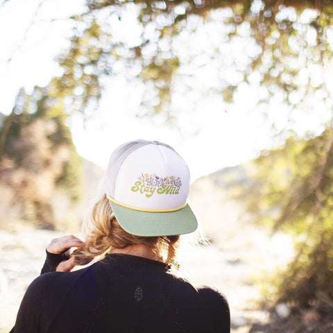 Woman wearing Stay Wild hat in nature, perfect for outdoor adventures with Trek Light style.