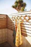 Sunny Wander & Travel Towel hanging in a sunny space, showcasing its vibrant sunshine design and practical use.