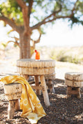 Sunny Wander & Travel Towel draped over a wooden stool in a sunny outdoor setting.