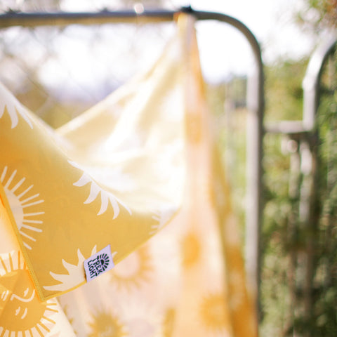 Sunny Wander & Travel Towel hanging on a clothesline, showcasing its bright design and quick-dry, sand-resistant features made from recycled materials.