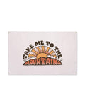 Take Me To The Mountains Canvas Flag in pale blush with a retro orange sunburst over mountains, brass grommets, on white
