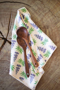 Texas Kitchen & Tea Towel with wooden utensils on a rustic wood surface, featuring vibrant floral design.