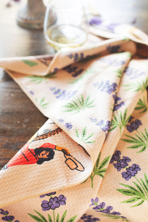 Texas Kitchen & Tea Towel featuring vibrant designs with flowers and a woman cooking, ideal for kitchen use.