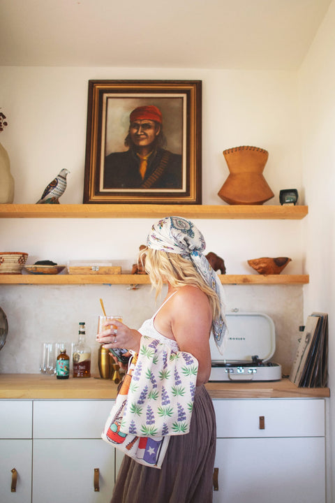 Woman in kitchen with Texas Kitchen & Tea Towel, showcasing vibrant design and eco-friendly features.