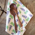 Texas Kitchen & Tea Towel with wooden utensils on a rustic wood surface, featuring vibrant floral design.