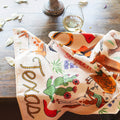 Texas Kitchen & Tea Towel featuring vibrant designs on a table with a glass of wine.