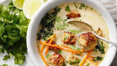 Delicious meatball soup with herbs, carrots, and lime served in a bowl, garnished with fresh cilantro.