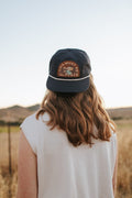 Person wearing This Must Be The Place Hat (Mountains) while enjoying a scenic outdoor view.