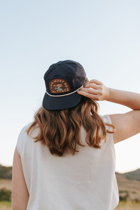 This Must Be The Place Hat (Mountains) worn outdoors with a scenic backdrop.