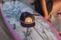 This Must Be The Place Hat (Mountains) placed on a surfboard, perfect for beach adventures.
