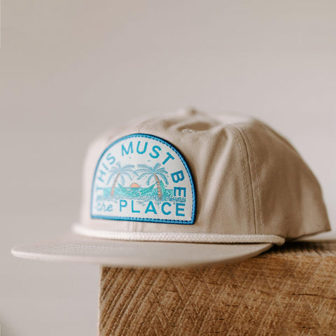 Trek Light's "This Must Be The Place" beach hat, unisex 6-panel snapback with flat brim and breathable vent holes, perfect for sunny adventures.