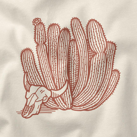 Illustration of a cactus with a cow skull graphic on a light beige shirt, designed by Trek Light Gear.