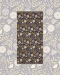 Travelin' Light Wander & Travel Towel in dark plum with cream and olive floral print, laid on a gray floral background.