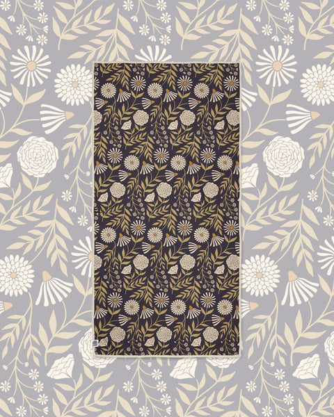 Travelin' Light Wander & Travel Towel in dark charcoal with cream and olive floral print, laid on a gray floral background.