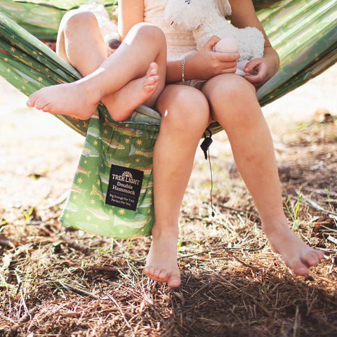 Two children relaxing in a Double Hammock & Pro Hanging Straps (River Trout Print) in a natural setting.