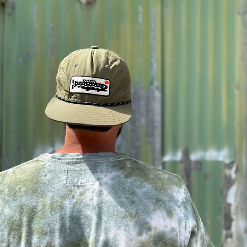 Man wearing a Trout Hat in olive green, showcasing its adjustable fit and stylish design.