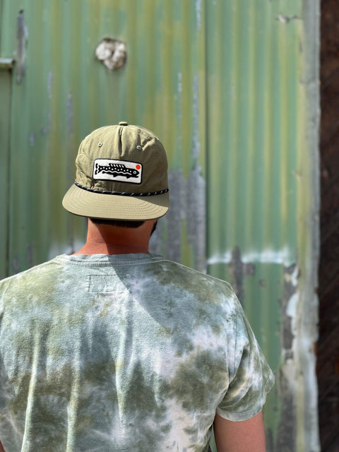 Man wearing a Trout Hat in olive green, showcasing its adjustable fit and stylish design.