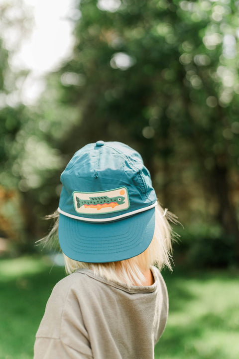 Trout Hat Twinsie Set displayed on a child's head in a sunny outdoor setting, featuring a vibrant design.