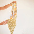 Wavy Flowers Kitchen & Tea Towel held up, showcasing its vibrant double-sided design and eco-friendly materials.
