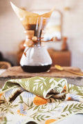 Wavy Flowers Kitchen & Tea Towel on a kitchen counter with coffee maker in the background.