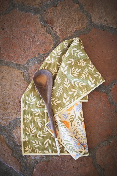 Wavy Flowers Kitchen & Tea Towel with a wooden spoon on a rustic background.