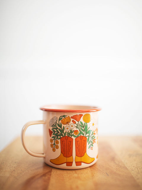 Western Bloom Enamel Mug 16oz with floral boot design by Trek Light on a wooden table, perfect for cozy sips.
