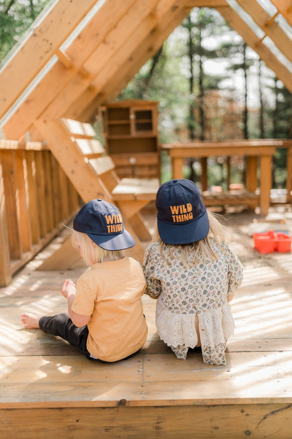 Kids wearing Wild Thing Kids Hats, enjoying playtime outdoors in a sunlit play area.