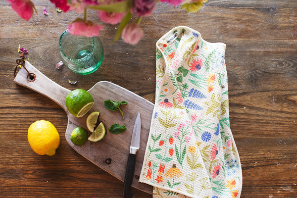 Wildflower Wonder Kitchen & Tea Towel on wooden surface with lemons and limes, showcasing its vibrant, eco-friendly design.