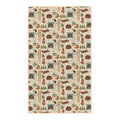 Winter Wonderland kitchen tea towel with illustrated cabins, wood stoves, skis, mittens, kettles and pine trees on cream