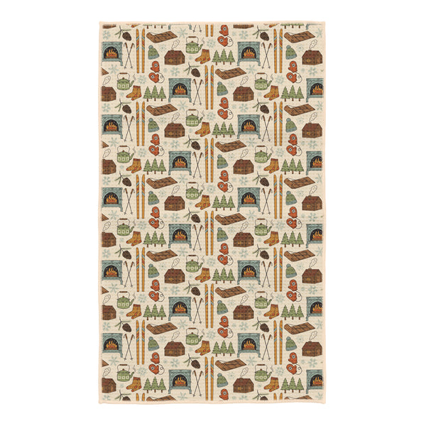 Winter Wonderland kitchen tea towel with illustrated cabins, wood stoves, skis, mittens, kettles and pine trees on cream
