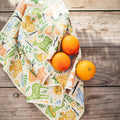 Woodland Friends Kitchen & Tea Towel with vibrant forest designs on wooden table with oranges, eco-friendly and super absorbent.