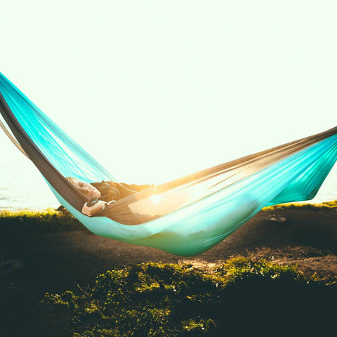 Relaxing in a Trek Light double hammock, aqua and charcoal, by the sea. Perfect for camping, travel, or backyard lounging.