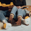 Couple wearing cozy You Are My Sunshine socks by Trek Light, lounging comfortably, showcasing stylish and breathable sock design.