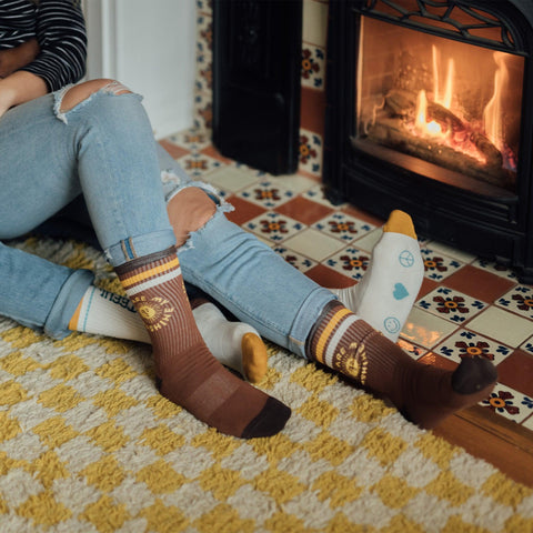 Cozy by the fire wearing Trek Light You Are My Sunshine Socks with perfect stretch and cushion for everyday comfort.