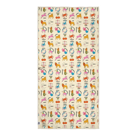 Zodiac patterned towel on cream background with scattered zodiac icons including lion, crab, scales, ram, and fish symbols in playful watercolor style