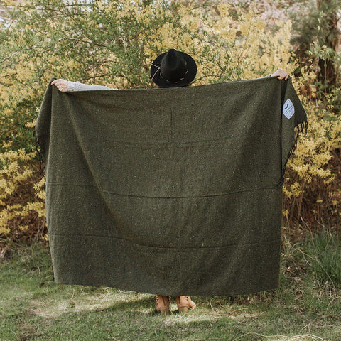 Cozy Humboldt Blanket by Trek Light, handwoven with recycled materials, held by person in nature; one tree planted per sale.