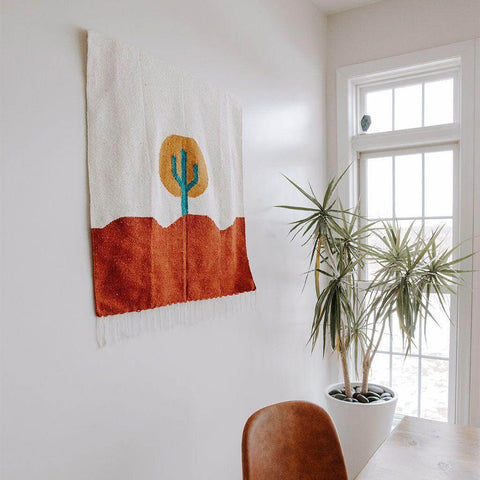 Trek Light Arizona Blankestry - handwoven desert scene tapestry hanging in a bright room, blending art and functionality.