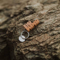 Trek Light BE KIND wood keychain on rustic rock background, featuring nickel split-ring. Unique hand-cut gift idea.